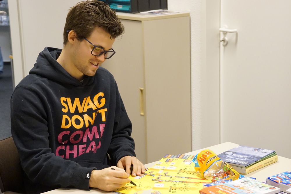 Magnus Carlsen firmando algunas de las cubiertas de los DVDs de Fritz 16 | Foto: Nadja Wittmann